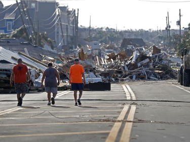 People walk amidst destruction on the main street of Mexico Beach, Fla., in the aftermath of Hurricane Michael on Thursday, Oct. 11, 2018.