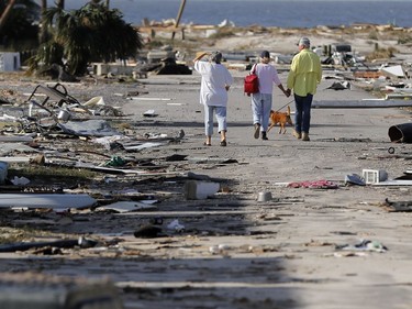 People hold hands as they walk amidst destruction in the aftermath of Hurricane Michael in Mexico Beach, Fla., Thursday, Oct. 11, 2018.