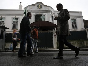 People walk by as members of the media report outside the Saudi Arabia consul general residence in Istanbul, Thursday, Oct. 18, 2018.