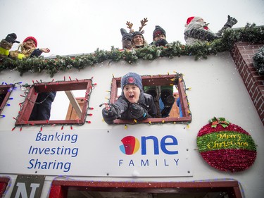 A young boy leans out of a float to share a candy cane at the 49th Annual Help Santa Toy Parade Saturday, November 17, 2018.  Ashley Fraser/Postmedia