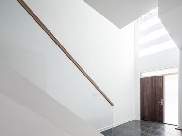 1208 home reno
The entryway of the home is fresh and bright with a contemporary glass-paneled staircase and wooden railing. A window sitting high above the door allows natural light to flood the open space.