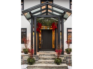 Speaking to the traditional exterior of the home, classic arrangements of red Ilex berries, crimson curly willow and Christmas greenery frame the front porch. But Jessica Barrett of Mill Street Florist adds a bit of the unexpected with giant red stars hanging under the portico.