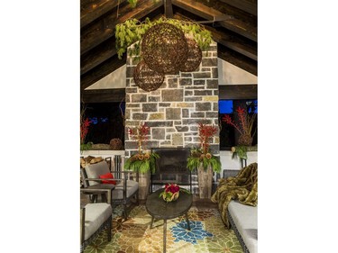 Once a single-car garage, the outdoor room with its working fireplace is now a chalet-like spot for relaxing. 'We spent our summer out here,' says the homeowner. Mill Street opted for more of a winter look than a Christmas one, aiming for an outdoor winter scene heavy on earthy elements such as wooden planters, B.C. cedar, giant pinecones and huge grapevine balls. Ilex berries and a few red roses provide a pop of colour.