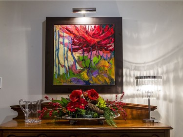 The dining room sideboard features a more traditional arrangement of amaryllis, Ilex berries and Christmas greenery.