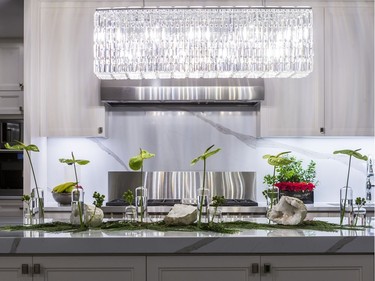 The white cabinets, counters and backsplash allow the airy arrangement on the kitchen island to stand out. 'I like taking inspiration from natural elements,' says Jessica Barrett of Mill Street Florist, who placed geodes (round rocks with a cavity lined with crystals) on a cedar runner interspersed with bud vases of anthurium and St. John's wort.