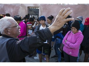 A volunteer who helped with the delivery of a donated breakfast, prays as Central American migrants wait in a line to receive the breakfast at a temporary shelter in Tijuana, Mexico, early Saturday morning, Nov. 17, 2018.