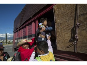 A boy is taken from a truck as Central American migrants arrive at the outskirts of Mexico City, Monday, Nov. 5, 2018. A big group of Central Americans pushed on toward Mexico City from a coastal state Monday, planning to exit a part of the country that has long been treacherous for migrants seeking to get to the United States.