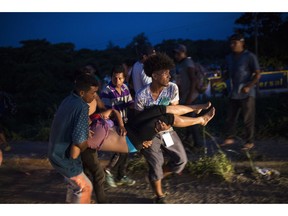Migrants carry a friend to an ambulance after suffering a heat stroke, at an abandoned hotel in Matias Romero, Oaxaca state, Mexico, Thursday, Nov. 1, 2018. Thousands of migrants arrived in the town of Matias Romero after an exhausting 40-mile (65-kilometer) trek from Juchitan, Oaxaca, where they failed to get the bus transportation they had hoped for.