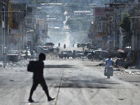 Haitian people are seen walking on the streets near remains of barricades from a protest the day before during a general strike in Port-au-Prince, on November 19, 2019. - Investigations by the Haitian Senate in 2016 and 2017 concluded that nearly $2 billion from a Venezuelan aid program called Petrocaribe were misused. Through Petrocaribe, Venezuela for years supplied Haiti and other Caribbean and Central American countries with oil at cut-rate prices and on easy credit terms.