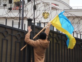 An activist sets a Ukrainian flag to the fence of Russian consulate during a protest action in Black Sea Ukrainian city of Odessa on November 26, 2018.