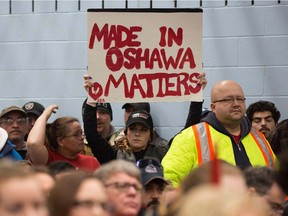 A woman holds a sign during the press conference with union leaders at Local 222 in Oshawa, on Monday. In a massive restructuring, US auto giant General Motors announced Monday it will cut 15 percent of its workforce to save $6 billion and adapt to "changing market conditions."