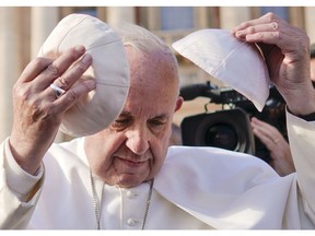 Pope Francis tries on a cap he was offered as he leaves at the end of his weekly general audience, in St. Peter's square, at the Vatican, Wednesday, Nov. 21, 2018.