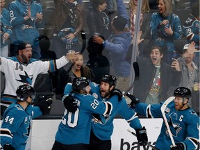 San Jose Sharks' Marc-Edouard Vlasic (44) and Marcus Sorensen (20) celebrate with teammate Joe Thornton, third from left, who scored his 400th career goal in the third period of an NHL hockey game against the Nashville Predators, in San Jose, Calif., Tuesday, Nov. 13, 2018.