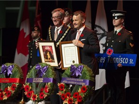 Ottawa Mayor Jim Watson and Minister of Veterans Affairs Seamus O'Regan present each other with the Veterans Week poster and the proclamation of Veteran's Week in Ottawa, during the Candlelight Tribute for Veterans at the National War Museum in Ottawa on Monday, Nov. 5, 2018. Watson says he sees smooth sailing ahead with the new city council.