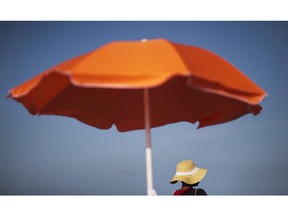 A woman sits next to an umbrella while looking out toward the ocean in Folly Beach, S.C. on Tuesday, June 16, 2015. A Health Canada review of sunscreens has found no new safety concerns, although the federal department found mild to moderate skin reactions can occur in people with a sensitivity to the products' ingredients on rare occasions.