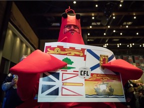 Dressed in a lobster costume, Dorothy MacDonald of Port Dover, Ont., who is originally from Nova Scotia, holds the flags of the maritime provinces as the Canadian Football League announces that Halifax's CFL team will be called the Atlantic Schooners during a Grey Cup week event in Edmonton on Friday.