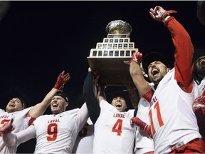 Laval University Rouge et Or quarterback Hugo Richard, centre, flanked by Vincent Desjardins, from left, Mathieu Betts (9) and Benoit Gagnon-Brousseau (11), raises the trophy as the team celebrates its victory against Western University Mustang at the Vanier Cup final Saturday, November 24, 2018 in Quebec City. Laval won 34-20.