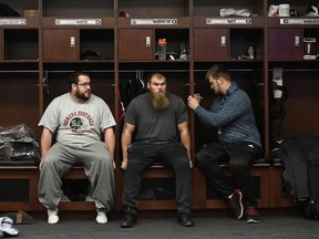 Redblacks players Alex Mateas (left) Jon Gott and Evan Johnson sit together as the team participates in media interviews and clear out of their locker room yesterday. All signs point to Gott not returning to play for the Redblacks next season.  Justin Tang/The Canadian press