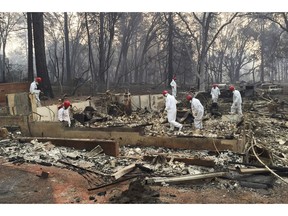 FILE - In this Nov. 15, 2018 file photo, volunteer rescue workers search for human remains in the rubble of homes burned in the Camp Fire in Paradise, Calif. Northern California officials have struggled to get a handle on the number of missing from the deadliest wildfire in at least a century in the United States. Authorities continue to log hundreds of reports by people who couldn't reach loved ones in the aftermath of the Camp Fire in Butte County.