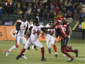 Redblacks linebacker Kyries Hebert (34)  and Stampeders receiver Eric Rogers eye a pass attempt that has deflected into the air, but will eventually fall harmlessly to the turf during Sunday's Grey Cup game in Calgary.