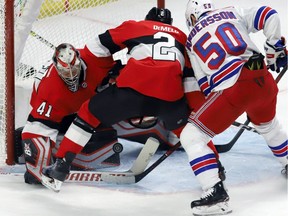 Ottawa Senators goaltender Craig Anderson (41) attempts to scoop up the puck as defenceman Dylan DeMelo and the New York Rangers' Lias Andersson (50) look for a rebound on Thursday, Nov. 29, 2018.