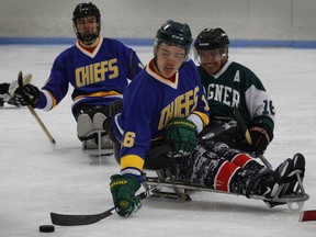 Humboldt Broncos hockey player Ryan Straschnitzki, middle, passes the puck away from Marty Richardson, right, as Broncos teammate Jacob Wassermann follows the play during a sled hockey scrimmage at the Edge Ice Arena in Littleton, Colo., on Friday, Nov. 23, 2018. Both players were paralyzed from the waist down in the team's bus crash in April.