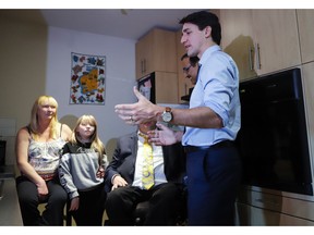 Prime Minister Justin Trudeau, right, speaks with Tracey Hume, left, and her granddaughter Desiree Hume, 11, in their apartment in Calgary, Alta., Thursday, Nov. 22, 2018.