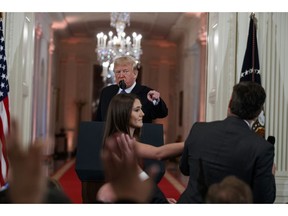 FILE - In this Nov. 7, 2018 file photo, President Donald Trump watches as a White House aide reaches to take away a microphone from CNN journalist Jim Acosta during a news conference in the East Room of the White House in Washington. CNN is suing the Trump administration, demanding that Acosta's press credentials to cover the White House be returned. The administration revoked them last week following President Trump's contentious news conference, where Acosta refused to give up a microphone when the president said he didn't want to hear anything more from him.