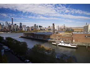 In this Wednesday, Nov. 7, 2018, photo, a rusting ferryboat is docked next to an aging industrial warehouse on Long Island City's Anable Basin in the Queens borough of New York. Across the East River is midtown Manhattan, top left. Long Island City is a longtime industrial and transportation hub that has become a fast-growing neighborhood of riverfront high-rises and redeveloped warehouses, with an enduring industrial foothold and burgeoning arts and tech scenes.