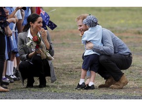 FILE - In this Oct. 17, 2018 file photo, Britain's Prince Harry and Meghan, Duchess of Sussex are embraced by Luke Vincent, 5, on their arrival in Dubbo, Australia. Prince Harry and his wife Meghan are on day two of their 16-day tour of Australia and the South Pacific.