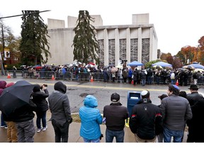 People line both sides of the street as they gather outside the Tree of Life Synagogue for a service on Saturday, Nov. 3, 2018, in Pittsburgh. About 100 people gathered in a cold drizzle for what was called a "healing service" outside the synagogue that was the scene of a mass shooting a week ago.