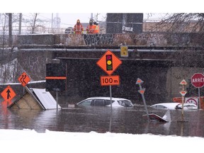 City workers look over a flooded street after a water pipe was perforated by a natural gas company doing work nearby in Montreal on Tuesday, November 20, 2018. The Atwater Tunnel, running under the Lachine Canal, was flooded cutting off a main corridor that links the downtown area to neighbourhoods to the south of the city.