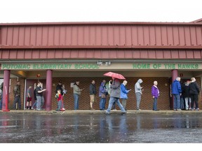 As rain falls, voters wait in line at the polling station located at Potomac Elementary School in Dahlgren, Va., Tuesday, Nov. 6, 2018.