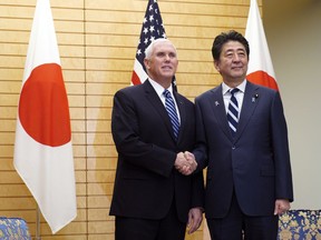 U.S. Vice President Mike Pence, left, shakes hands with Japanese Prime Minister Shinzo Abe at Abe's official residence in Tokyo Tuesday, Nov. 13, 2018.