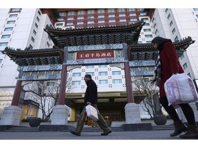 Residents passes by The Peninsula hotel which announced that it was investigating claims in an online video that supposedly showed the hotel cleaners using dirty towels to wipe cups and sinks in Beijing Friday, Nov. 16, 2018. The Chinese tourism ministry asked authorities in Beijing, Shanghai and three provinces to investigate room cleaning at 14 major hotels after hidden camera video showed workers using used towels to clean cups and glasses and other questionable practices.