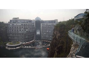 Visitors walk near the Intercontinental Shanghai Wonderland Hotel in Songjiang district of Shanghai, east China, Thursday, Jan. 15, 2018. The 18-story hotel has been built into the side of a huge hole in the ground left by a former put mine with sixteen of its floors below ground level. (AP Photo)