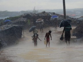 In this file photo taken on October 12, 2017, a Rohingya refugee child carries water during rain in a refugee camp at Kutupalong refugee camp in Bangladesh's Ukhia district.