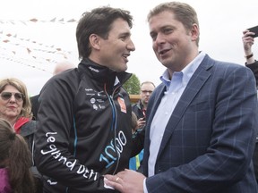 Prime Minister Justin Trudeau, left, shakes hands with Conservative Leader Andrew Scheer at the start of the Defi Pierre Lavoie, a 1000km bicycle trek, in June in Saguenay Que.Which of the two will be prime minister a year from now?