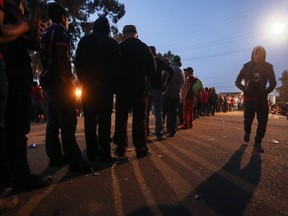 Migrants wait in line to receive dinner outside a temporary shelter set up for members of the 'migrant caravan' on November 27, 2018 in Tijuana, Mexico.