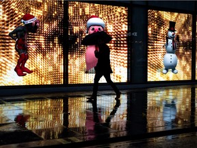 A digital window display features dancing Christmas characters as shoppers brave the rain on Oxford Street.