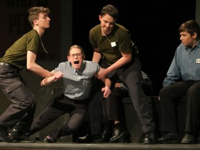 Guards, played by Frank Deslandes (L) and Andrew Belanger (2ndFR), Syme played by Sophie Holcik (2ndFL), and Parsons played by Jack Bradley (R), during St. Pius X High School's Cappies production of 1984, held on November 28, 2018, in Ottawa, ON.