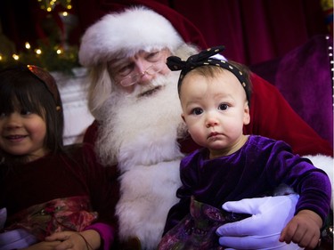 Ten-month-old sister Quiana Cormier appears a bit perplexed while visiting Santa with her five-year-old sister, Thea, left.