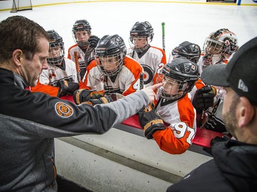 Philadelphia Little Flyers, including #97 Cole Gargon, gathered at the boards for a pep talk and to listen to the coaches.