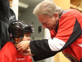 Eugene Melnyk ties the helmet of Eh Nay Soe Kyu of D Roy Kennedy school during the 15th annual Eugene Melnyk Skate for Kids at the Canadian Tire Centre on Thursday, Dec. 20, 2018.