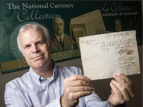 David Bergeron, curator with the Bank of Canada Museum, holds the oldest cheque in their collection from 1690. Errol McGihon/Postmedia