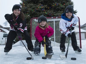 Sisters Sydney, 9, Molly, 4, and Emma Cosgrove, 8, on the family outdoor rink after school. The Cosgroves had to remove the boards from the rink to comply with a city bylaw following a neighbour's complaint.
