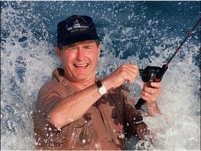 In this file photo taken on November 14, 1988 president elect George Bush is smashed by a wave 14 November 1988 while fishing in back of the home of William Farish in Florida.
