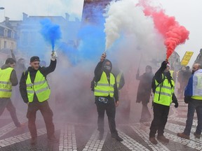Protesters light flares in the colours of the French flag during a "Yellow Vest" (Gilets jaunes) anti-government protest on Dec. 22 in Bordeaux, southwestern France.