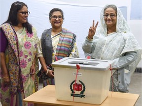 Bangladeshi Prime Minister Sheikh Hasina, right, flashes the victory symbol after casting her vote as her daughter, Saima Wazed Hossain, left, and her sister, Sheikh Rehana, look on at a polling station in Dhaka on Sunday.