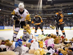 The Wilkes-Barre/Scranton Penguins' Sam Lafferty, left, helps gather teddy bears thrown on the ice with help from Lehigh Valley Phantoms players Mark Friedman, center, and T.J. Brennan, right, during an American Hockey League game at Mohegan Sun Arena in Wilkes-Barre, Pa. on Dec. 15.